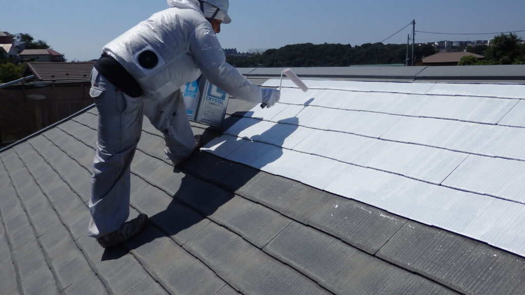 屋根上で塗装作業中の職人