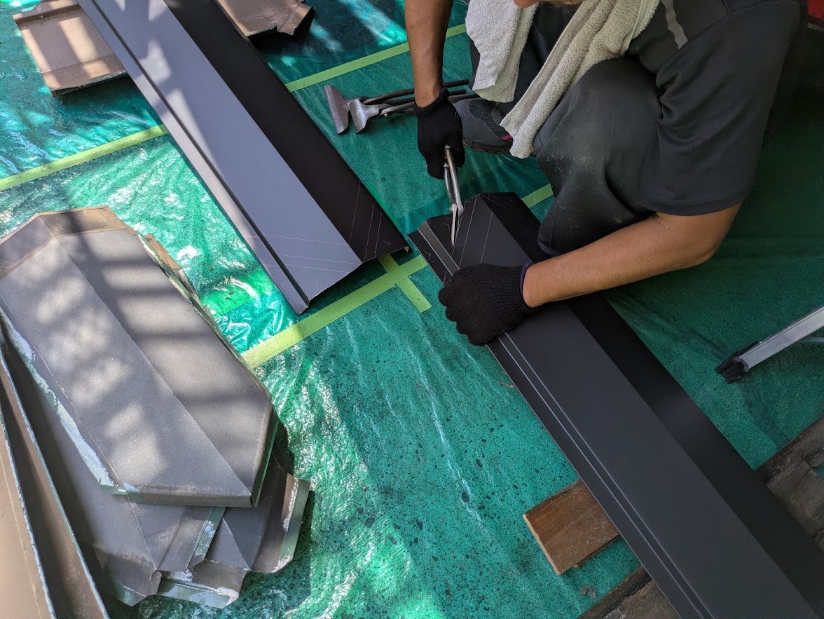 金切りばさみで新しい棟板金の端部を加工する作業 金切りばさみで新しい棟板金の端部を加工する作業